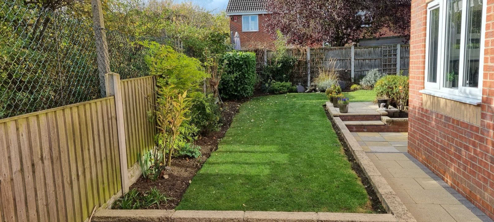 A landscaped side garden with clean brick borders, new planting and a neat lawn